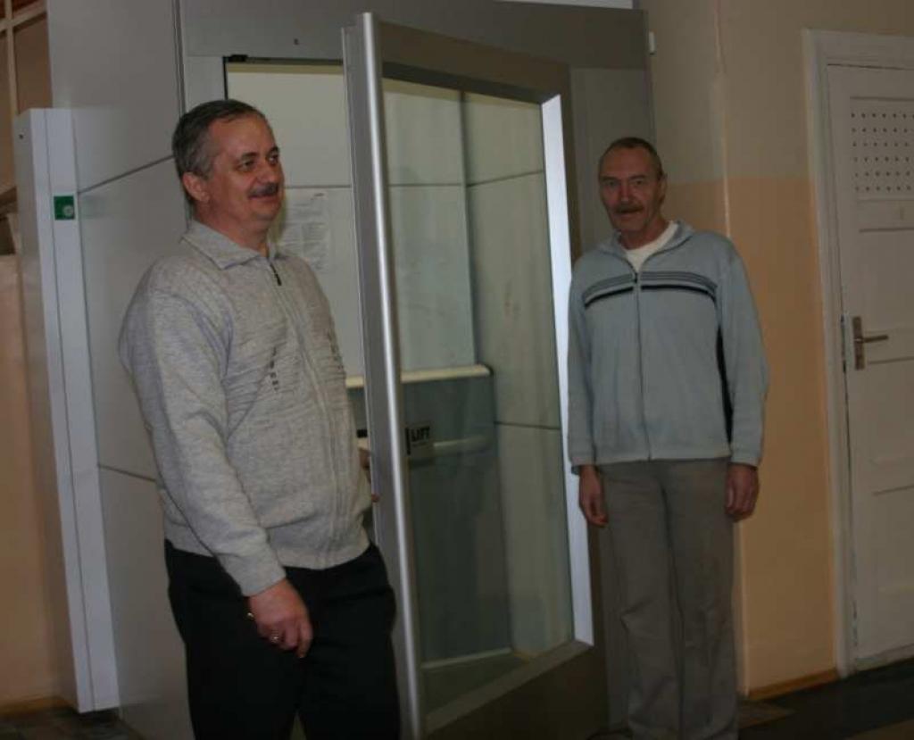 Centra direktors Jānis Kļaviņš (no kreisās) stāsta, ka pacēlājs ir domāts klientiem ar kustību traucējumiem, kā arī visiem tiem, kam ir grūti pašiem pārvietoties. 