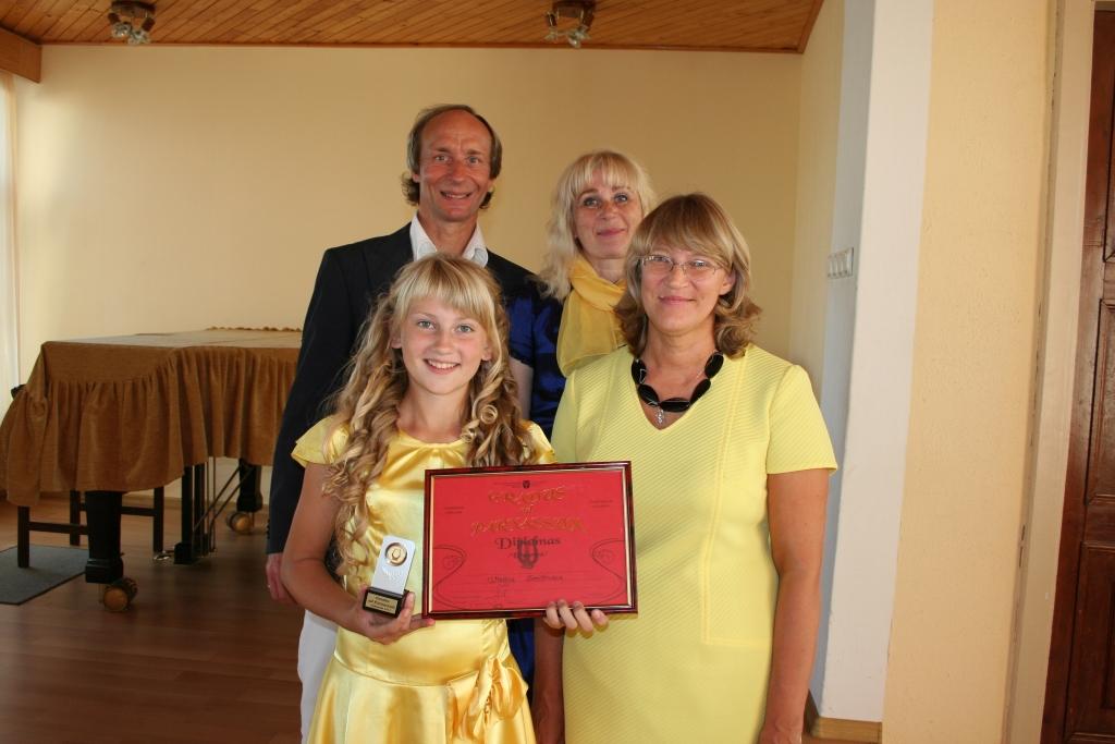 Ar Megijas Smiltnieces panākumiem starptautiskajā konkursā lepojas gan žūrijas komisijas loceklis Gatis Evelons, gan arī Megijas skolotāja Inga Driķe (pirmajā rindā no labās) un koncertmeistare Sarmīte Semjonova.
Autors:  Evita Brokāne