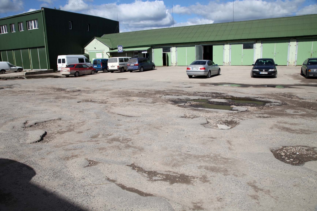 Lai autovadītājiem kuri pārvietojas pa šo laukumu, nenāktos bojāt savus transportlīdzekļus, zemes īpašniekiem un telpu nomniekiem ir jāvienojas, kā aizlāpīt bedres. 												    
Autors: Gatis Bogdanovs