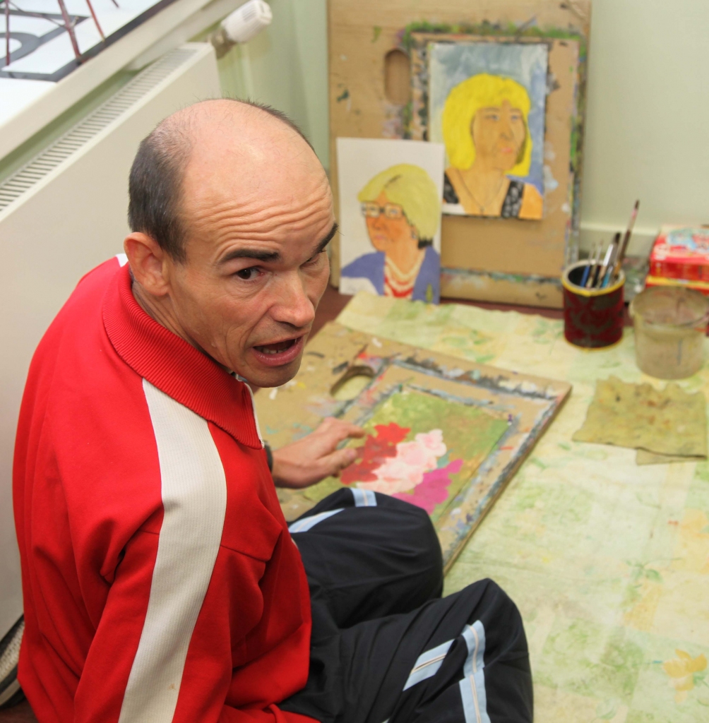 Ainars Pūrītis rāda, kādas gleznas viņam ir tapušas. Viņam padodas ne tikai dabasskati. Ar portretu zīmēšanu viņš iepriecina aprūpes centra darbinieces. 
Autors: Gatis Bogdanovs