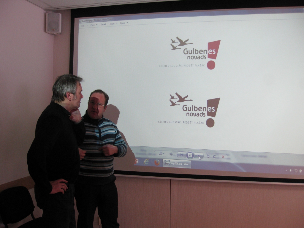 Radošs satraukums. Tā var teikt par dizaineri Ilmāru Drīliņu (no kreisās), prezentējot logo gala variantu. “Neaizmigu līdz pulksten 4.00,” viņš teica. Deputātam Dzintaram Poļakam logo patika. 
Autors: Diāna Odumiņa