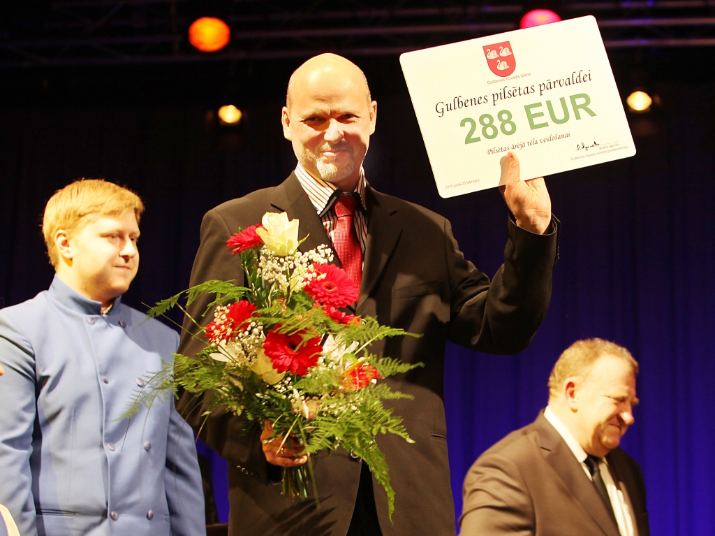Gulbenes pilsētas pārvaldes vadītājs Gints Āboliņš neslēpj prieku, saņemot Gulbenes novada domes pasniegto dāvanu karti 288 eiro vērtībā. Izmantojot tikai šo summu vai arī pieliekot klāt vēl kādu summu, būs iespējams iegādāties kaut ko vajadzīgu Gulbenes pilsētai. 
Autors: Gatis Bogdanovs
