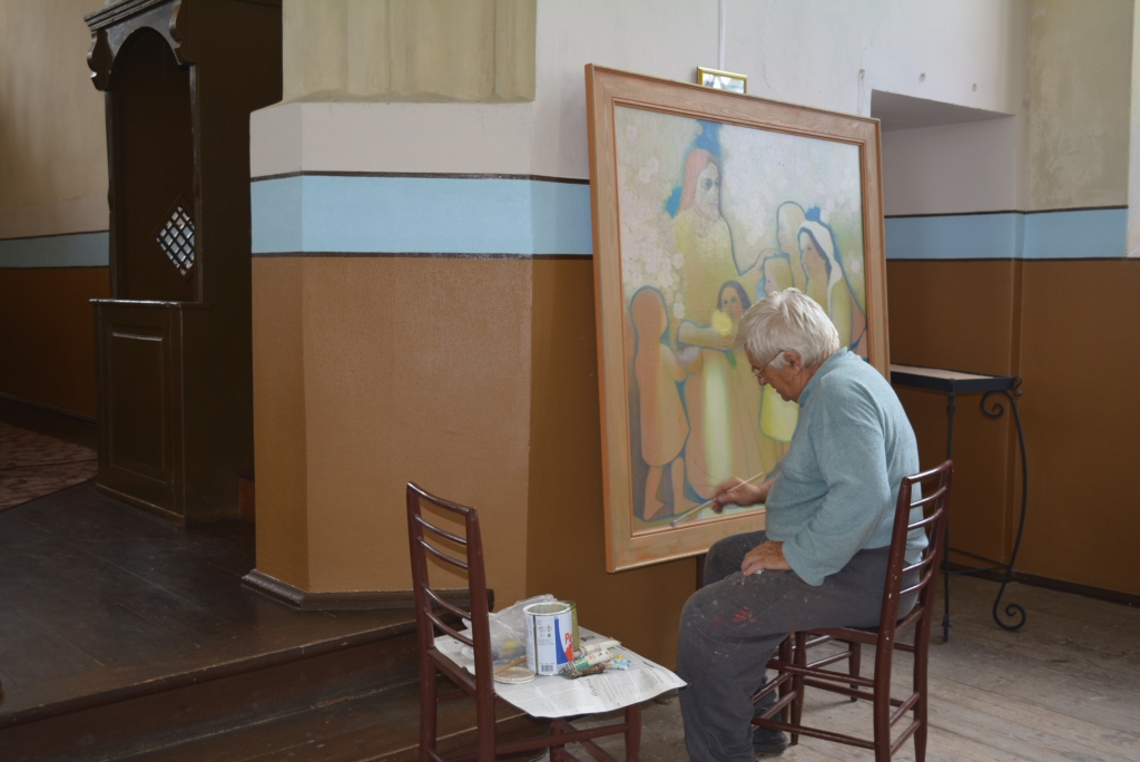 Mākslinieks Pēteris Postažs Velēnas baznīcā atjaunoja savu dievnamam dāvāto gleznu, padarot košākus krāsu kontrastus. 
Autors: no Lizuma pagasta arhīva