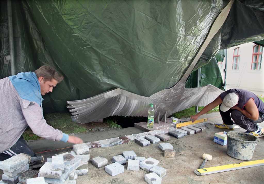 SIA “Valpor” strādnieki bruģē saules pulksteņa pamatni. Lai lietus laikā darbu nepārtrauktu, izveidots brezenta pārsegums. 
Autors: Gatis Bogdanovs