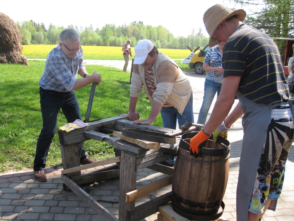 Trīs vīri un “varmāka”. Vajadzīgs liels spēks, lai uzmauktu mucai otru stīpu. Arī darot to ar mehānismu, vajadzīgi trīs vīri.  
Autors: Pārsla Konrāde