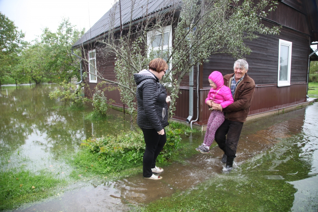 Gulbeniete Anita Bombaka no rīta gribēja mazo meitu Karīnu vest uz bērnudārzu, bet sācis stipri līt, tāpēc viņa ar meitu nolēmusi apraudzīt savu tēvu, kas dzīvo netālu no viņas. “Sākumā nemaz tik traki vēl nebija, bet pusstundas laikā ūdens līmenis pamatīgi pacēlās. Desmit gadus es pati dzīvoju blakus šai mājai, bet nebiju redzējusi, ka tā tik pamatīgi applūstu,” stāsta Anita, kuras meitai Karīnai izpalīdzīgais kaimiņš Aivars Mezītis palīdz tikt ārā no vectēva mājas. 
Autors: Gatis Bogdanovs