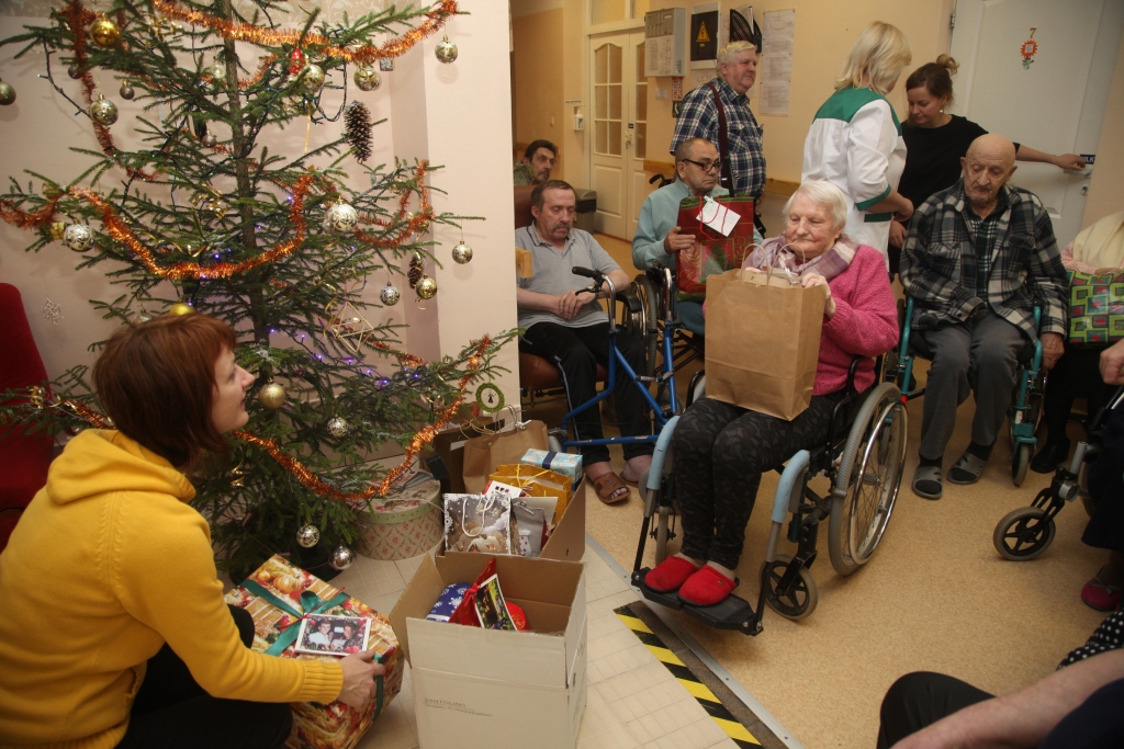 Trešdienas rītā sociālās aprūpes centra “Dzērves” klienti pulcējās pie Ziemassvētku eglītes, lai saņemtu dāvanas. Bija gan našķi, gan pavisam praktiskas lietas.  												  Foto: Gatis Bogdanovs