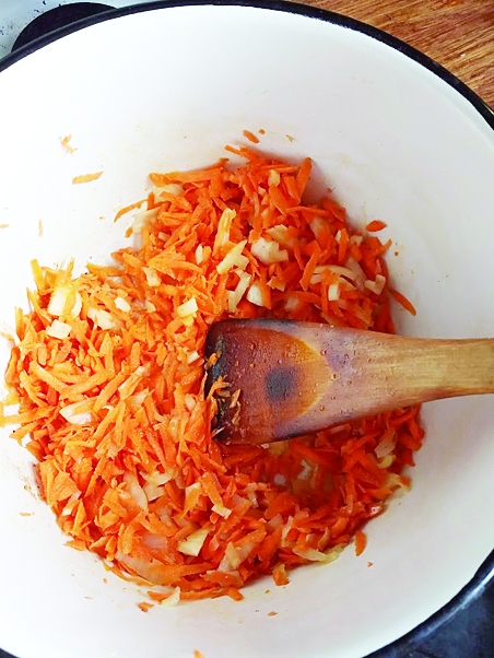 Burkānus nomazgā, nomizo un uz rīves sarīvē. Sīpolu un papriku smalki sagriež. Katlā nedaudz apcep burkānus un sīpolus, līdz maisāmā lāpstiņa un sīpoli nedaudz sāk iekrāsoties. Tad pievieno papriku un pacep vēl nedaudz. 
Autors: Liene Andersone-Kolosova