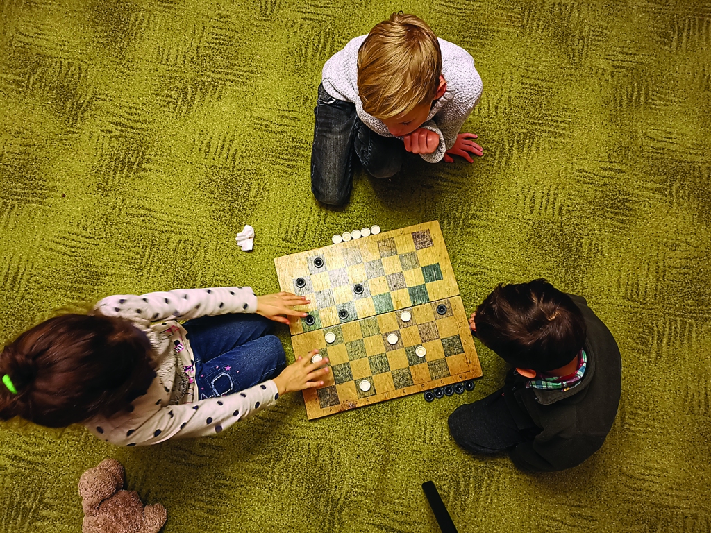 “Lielie bērni, kas skolā pulciņā apgūst dambreti, pacietīgi māca noteikumus mazākajiem. Dambretes spēles laukumu var arī pašrocīgi izveidot uz lielākas papīra pamatnes.” 	
Autors: Viktorija Slavinska-Kostigova