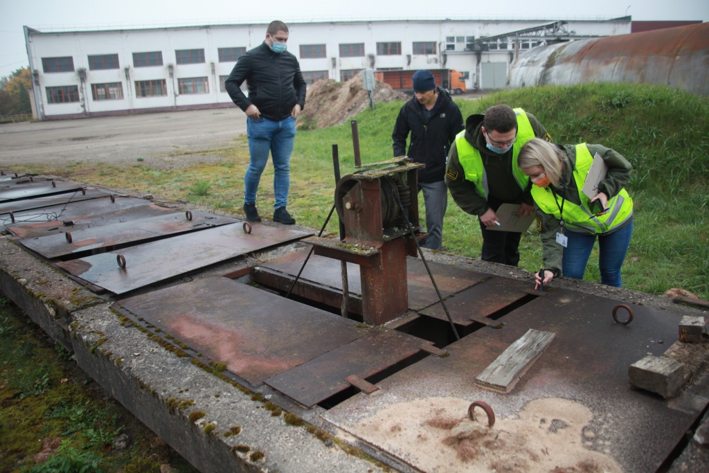 Kas tā par pazemes šahtu ar eļļainu šķidrumu? Kādam nolūkam tā ir kalpojusi? Uzmanību dīvainajam objektam pievērsa vides inspektori Jānis Zagorskis (otrais no labās) un Anete Šteinberga. Objekts atrodas SIA “Gulbenes nami” teritorijā Šķieneros (netālu no katlumājas), kur agrāk saimniekojusi SIA “Gulbenes Energo”. Valsts vides dienests uzdeva sākumā šahtu turēt noslēgtu un vēlāk gādāt par tās likvidēšanu. 	
Autors: Gatis Bogdanovs