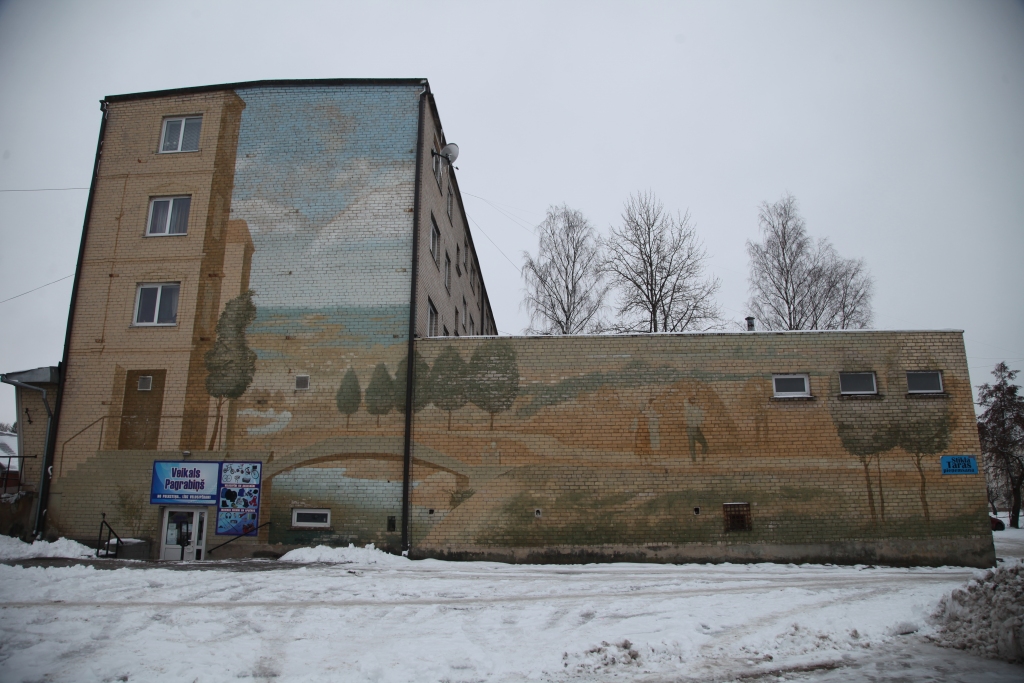 Šis sienas gleznojums Rīgas ielā Gulbenē tapa pēc tam, kad 1985.gadā Mākslas akadēmiju beidza Ivars Balodis, kurš vienu brīdi strādāja Lejasciema vidusskolā, kā arī bija mākslinieciskās padomes priekšsēdētājs Gulbenes pilsētā. Gleznojumā autors kopā ar kolēģi profesionālo mākslinieku Romānu Ivanovski vēlējās uzsvērt – Gulbenē ienāk lauki vai otrādi. Glezna veidota siltos zemes toņos.  
Autors:  Gatis Bogdanovs